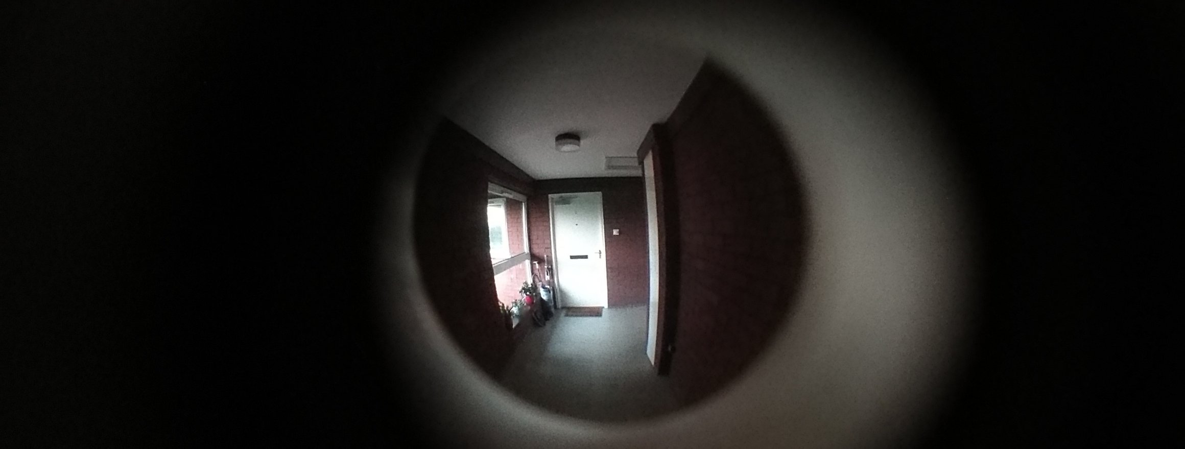 Blick durch den Türspion in einen leeren Flur