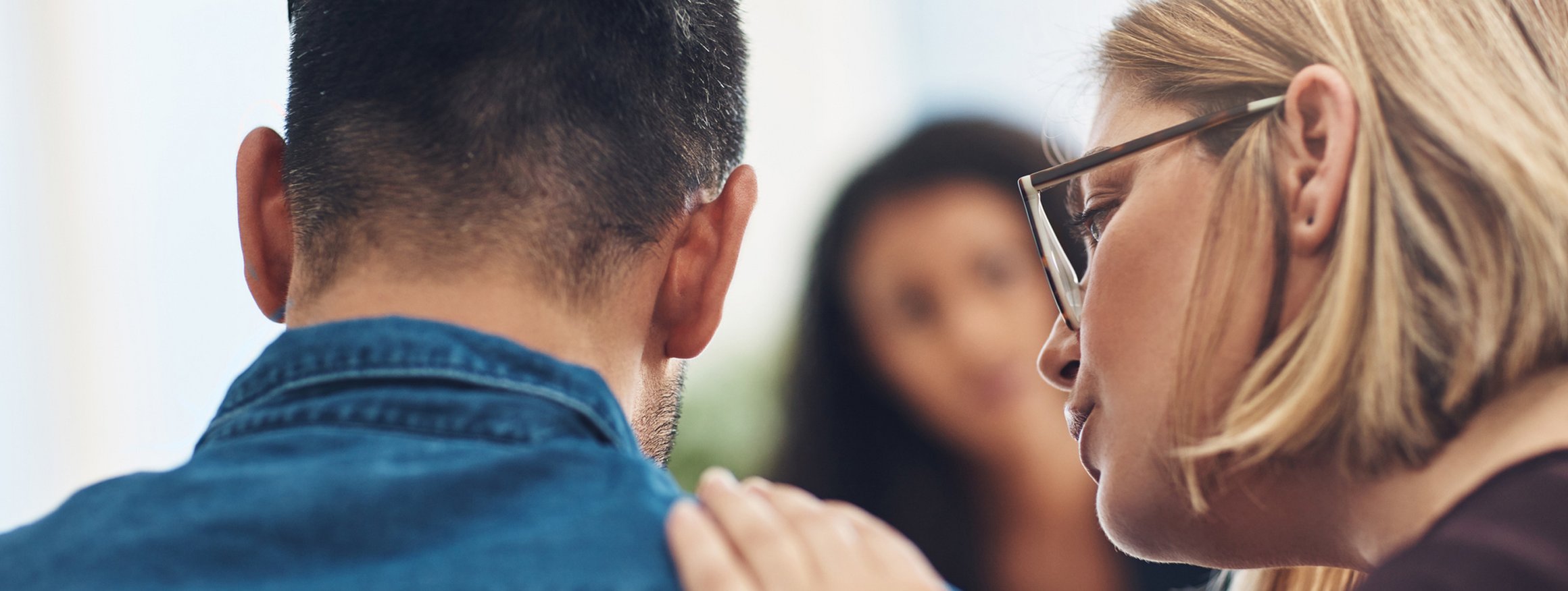 Eine Psychotherapeutin legt verständnisvoll mit Gefühl, ihre Hand auf die Schulter ihres Klienten