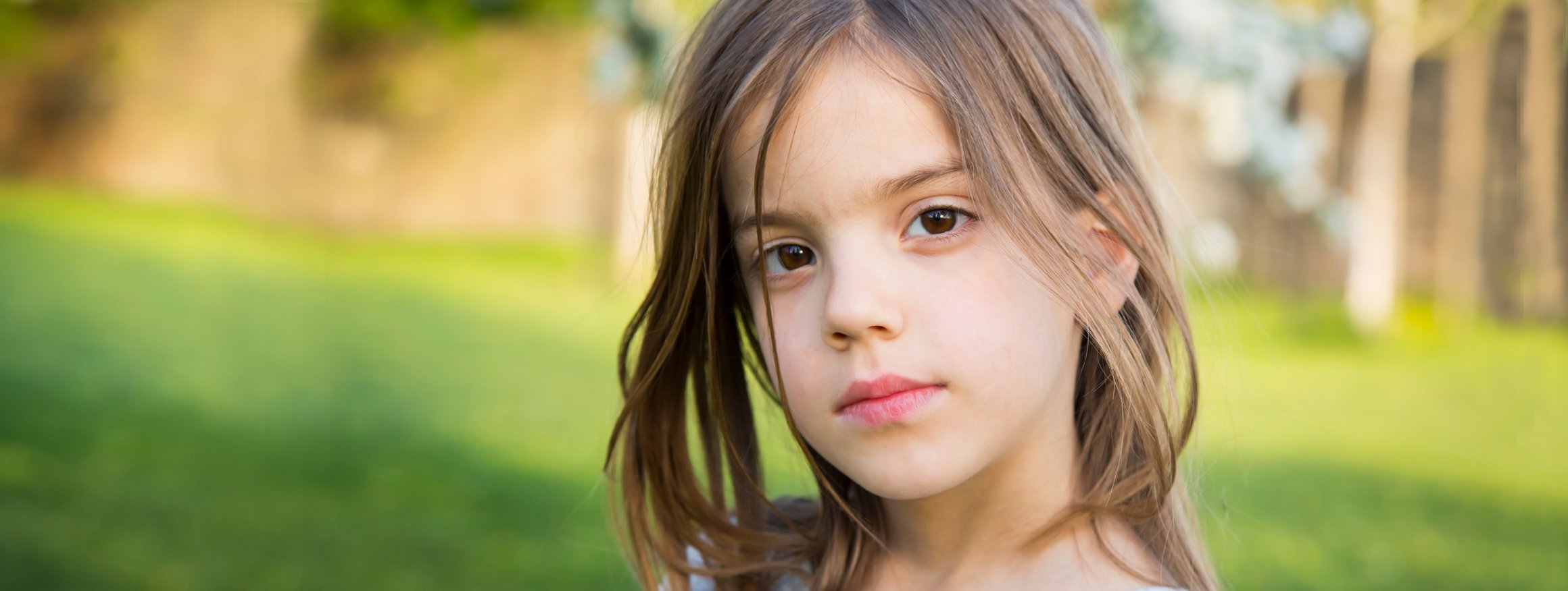 Ein Mädchen schaut ist schweigsam im Kindergarten und schaut dabei nachdenklich, während sie zuhause munter drauflosplappert