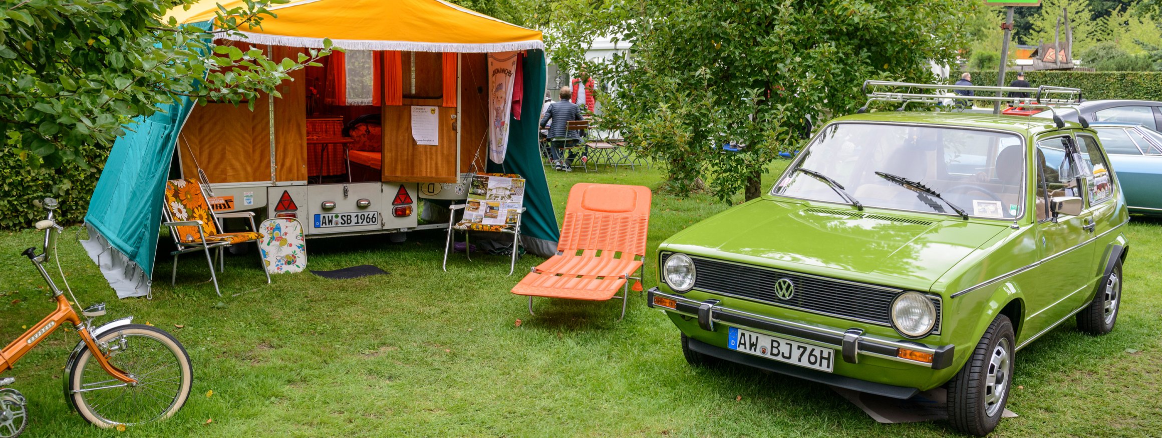Ein grüner 1-er VW Golf steht auf einem nostalgischen Campingplatz