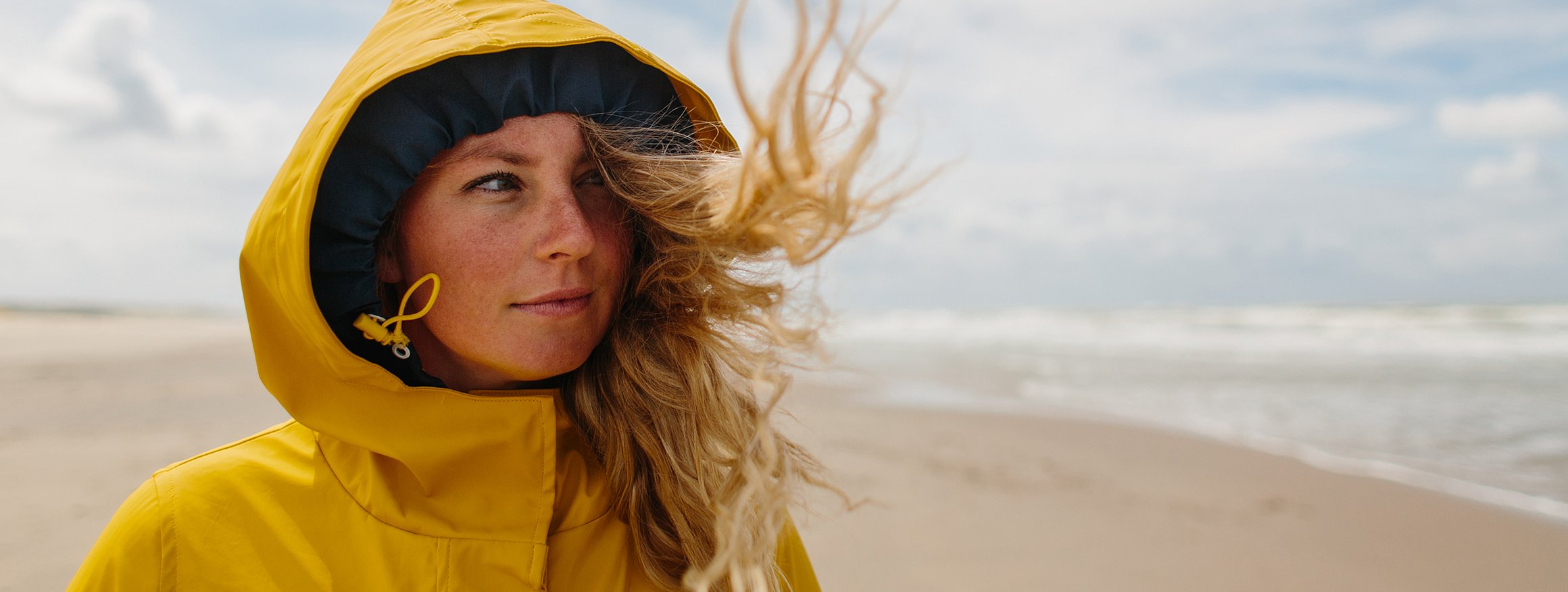 Foto zeigt eine junge Frau am Strand, die nach vorne schaut. 