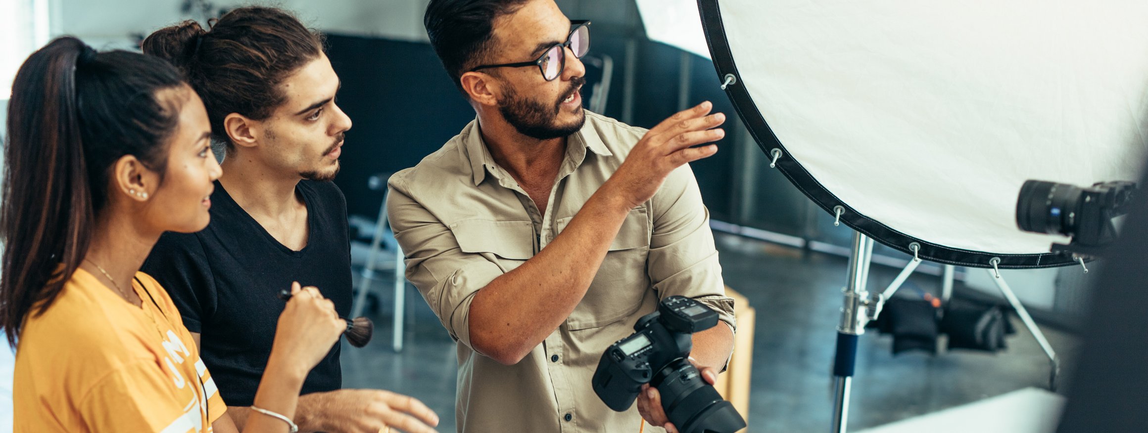 Ein Fotograf ist im Gespräch mit Kolleginnen während eines Shootings