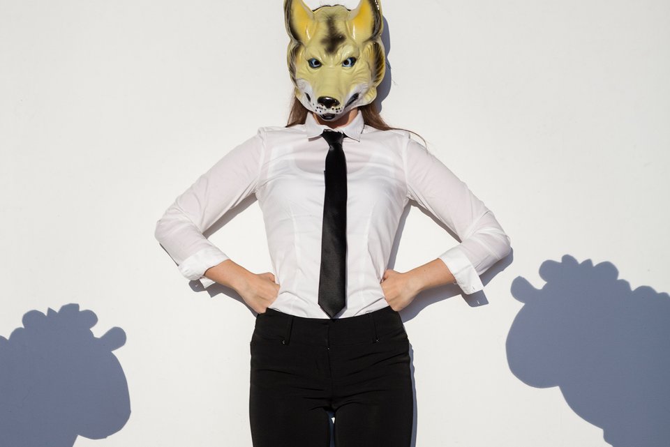 Foto zeigt eine Frau mit Businesskleidung und Wolfsmaske.