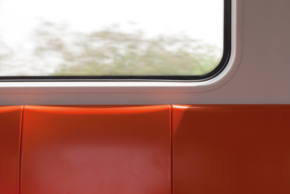 Eine rote Bank in einer S-Bahn mit Aussicht aus dem Fenster