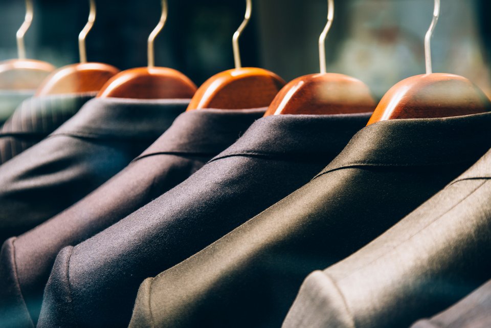 Eine Reihe von Anzügen auf Kleiderbügeln auf einer Kleiderstange