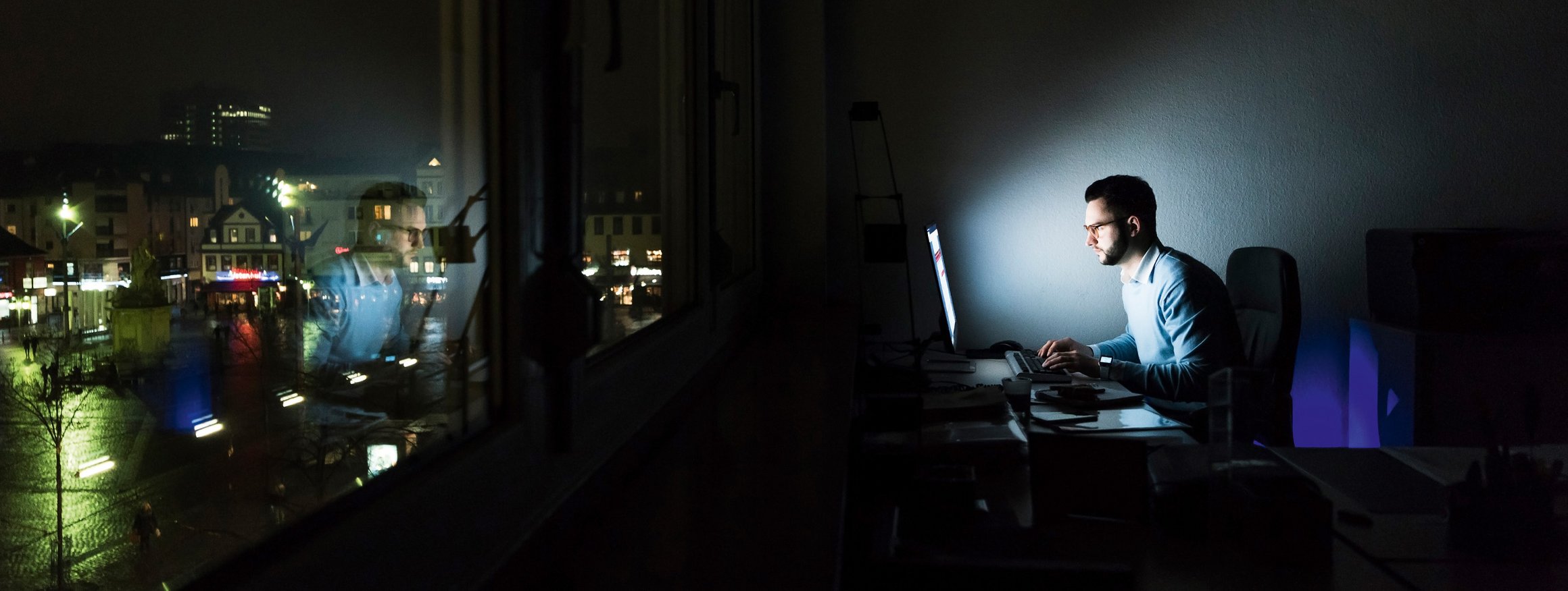 Foto zeigt einen Mann, der nachts am Computer arbeitet.