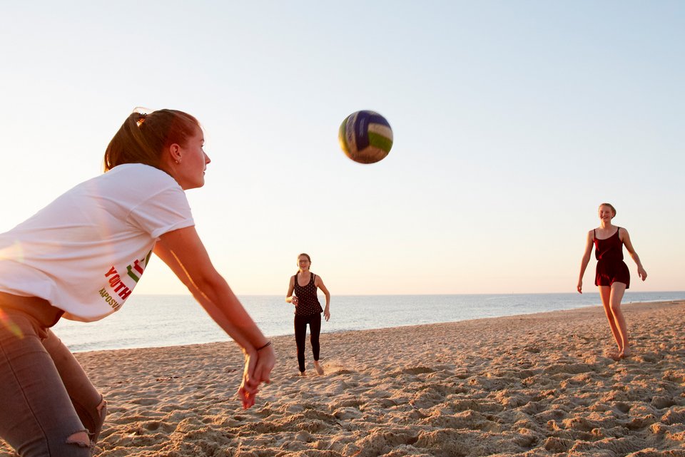 Drei junge Frauen spielen an einem Strand Beachvolleyball