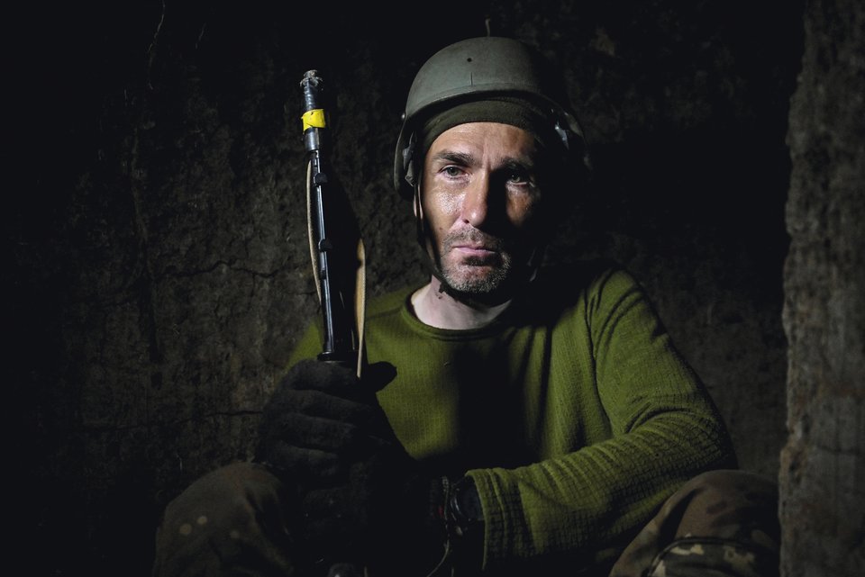 Ein ukrainischer Soldat wartet mit ernstem Gesicht in einen Graben an der Front im September 2022