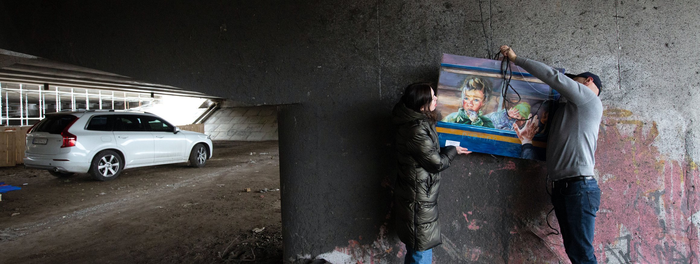 Zum Jahrestag der Befreiung von der russischen Besatzung hängen eine ukrainische Frau und ein Mann ein Kunstgemälde auf zu einer Ausstellung in Kiew