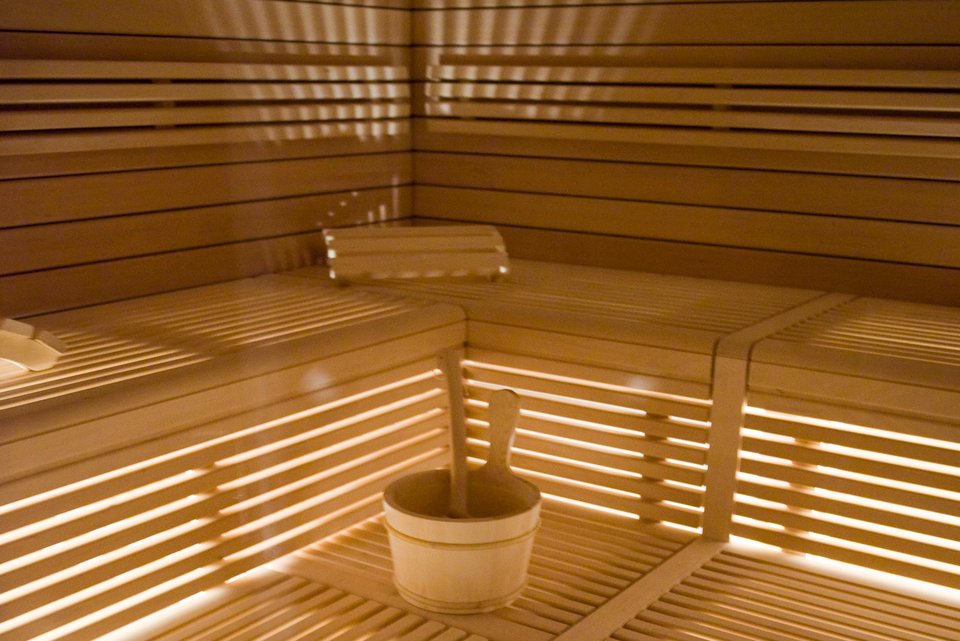 Eine Saunabank mit einem Aufgusseimer, alles aus Holz