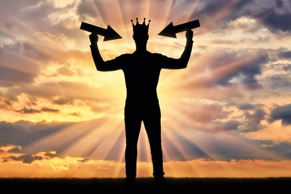 Die Silhouette einen Mannes, der eine Krone trägt und in Siegerpose im Sonnenuntergang dasteht, daneben sind zwei Pfeile, die auf ihn zeigen