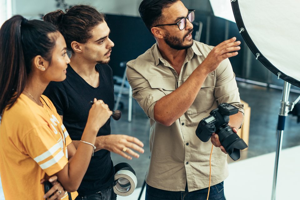 Ein Fotograf ist im Gespräch mit Kolleginnen während eines Shootings