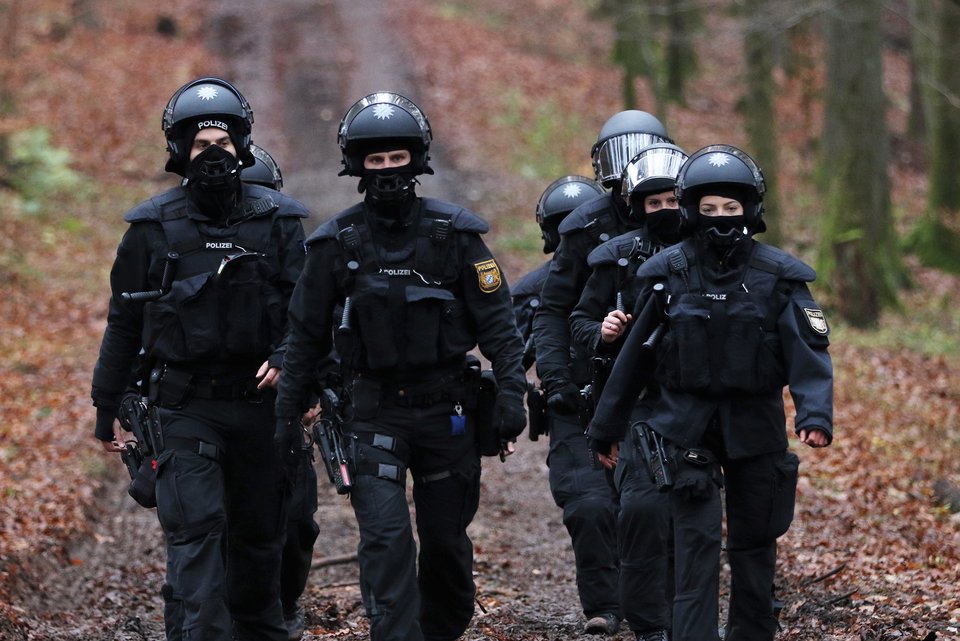 Eine Gruppe von Polizistinnen und Polizisten mit Helmen und schwarzer Einsatzkleidung laufen auf einem Waldweg in Richtung Dannenröder Forst