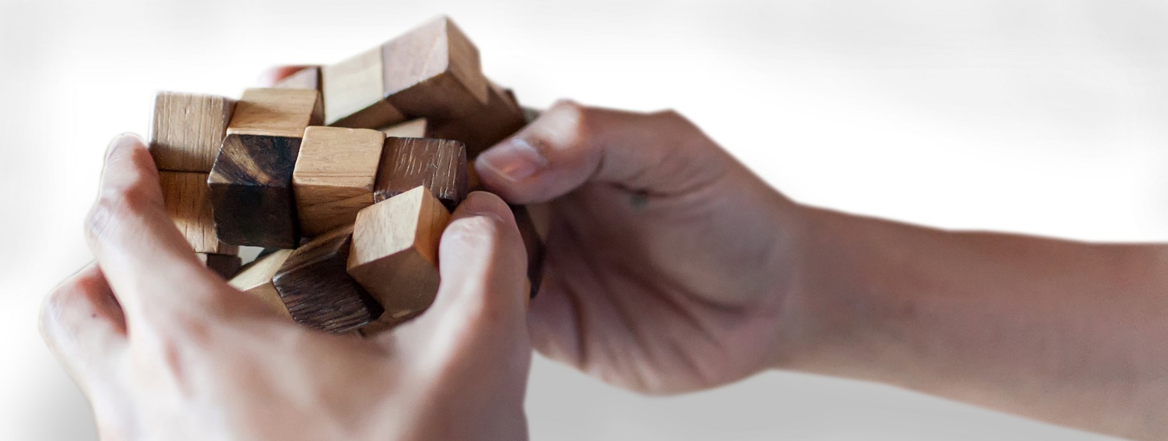 Zwei Hände halten einen Holzzauberwürfel und lösen das Spiel auf schnelle Weise